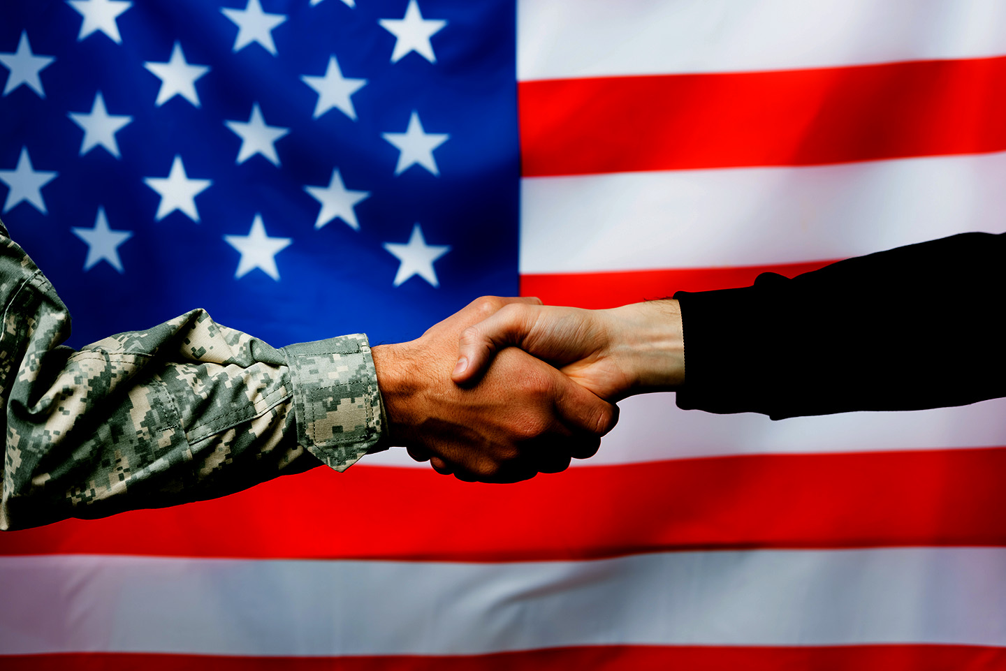 Veteran shaking hands with picture of american flag in the background