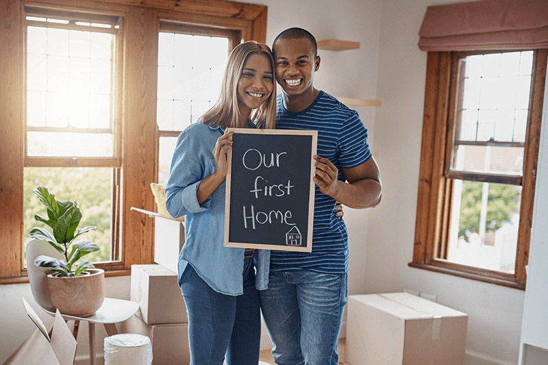 First time home buyers holding up a sign in their new home